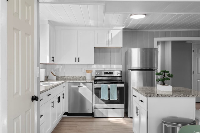 kitchen featuring white cabinetry, light hardwood / wood-style flooring, stainless steel appliances, and light stone counters