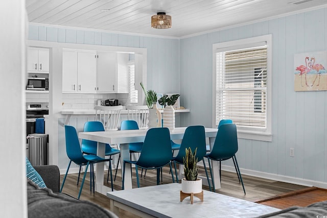 dining space with wood-type flooring, crown molding, and wooden walls