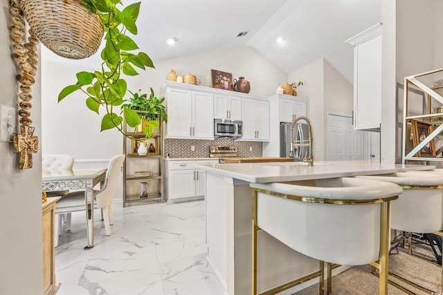 kitchen featuring appliances with stainless steel finishes, a breakfast bar, and white cabinetry