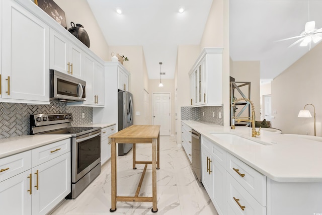 kitchen with backsplash, ceiling fan, stainless steel appliances, and white cabinets