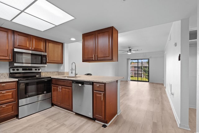 kitchen with light hardwood / wood-style floors, kitchen peninsula, stainless steel appliances, ceiling fan, and sink