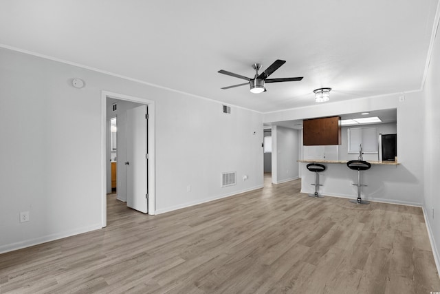 unfurnished living room with light hardwood / wood-style floors, ceiling fan, and crown molding