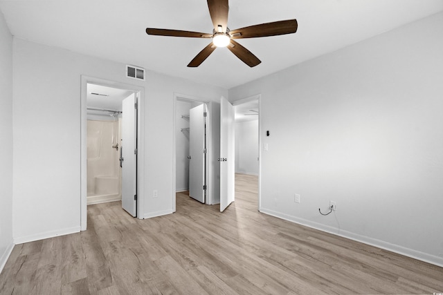 unfurnished bedroom featuring light hardwood / wood-style flooring, connected bathroom, ceiling fan, and a spacious closet