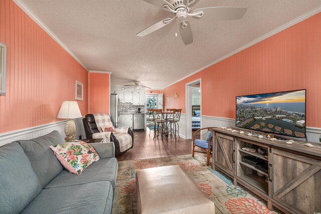 living room with ceiling fan, hardwood / wood-style flooring, ornamental molding, and a textured ceiling