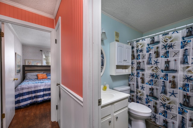 bathroom with vanity, a textured ceiling, hardwood / wood-style floors, ornamental molding, and toilet