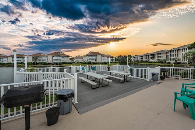 patio terrace at dusk featuring a deck with water view