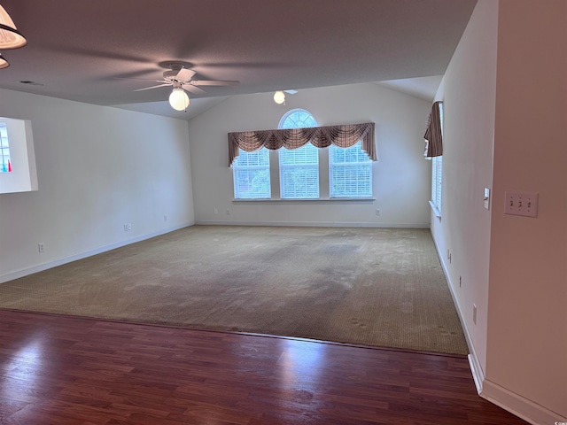 unfurnished room with vaulted ceiling, dark colored carpet, and ceiling fan