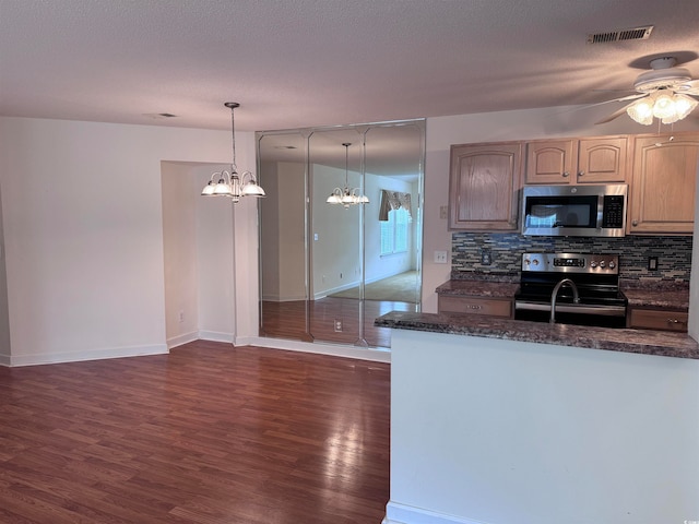 kitchen with ceiling fan with notable chandelier, dark wood-type flooring, stainless steel appliances, and decorative light fixtures