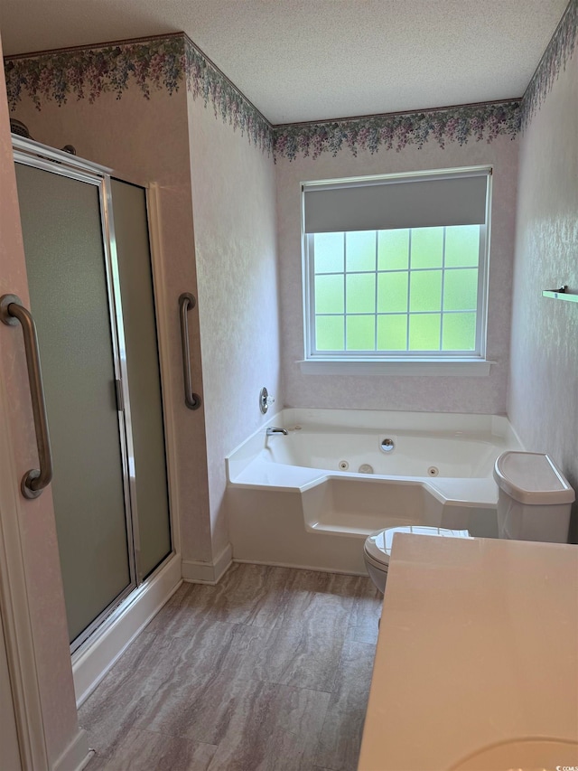 bathroom with a textured ceiling, plus walk in shower, hardwood / wood-style floors, and toilet