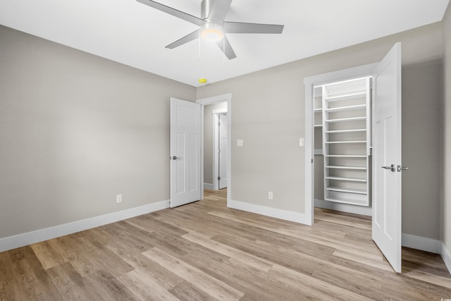 unfurnished bedroom featuring ceiling fan, light hardwood / wood-style floors, a walk in closet, and a closet