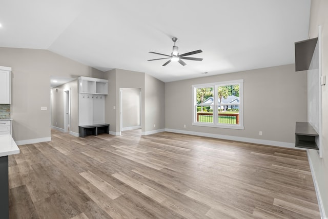 unfurnished living room featuring light wood-type flooring, vaulted ceiling, and ceiling fan