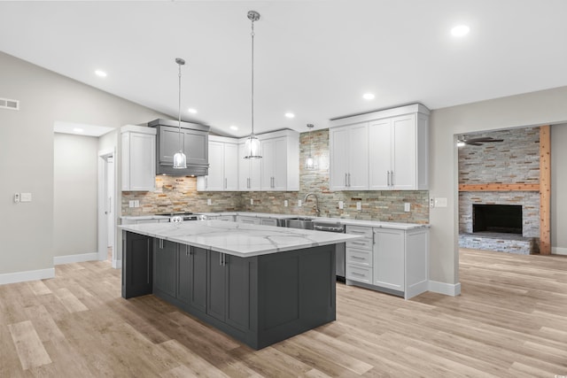 kitchen with tasteful backsplash, white cabinets, a spacious island, and decorative light fixtures