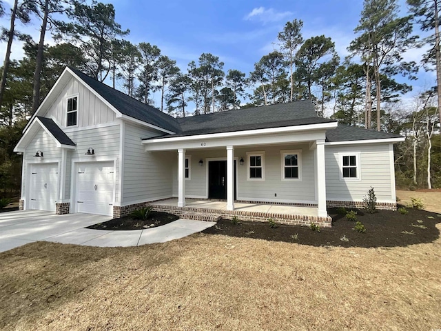 modern inspired farmhouse featuring driveway, covered porch, a shingled roof, a garage, and board and batten siding