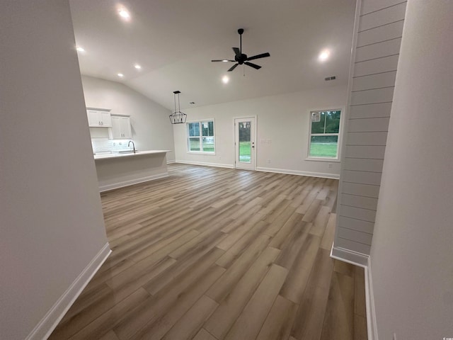 unfurnished living room featuring light wood-type flooring, vaulted ceiling, ceiling fan, and sink