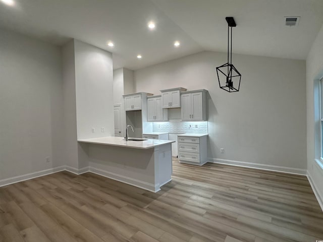 kitchen featuring kitchen peninsula, vaulted ceiling, sink, and light hardwood / wood-style flooring