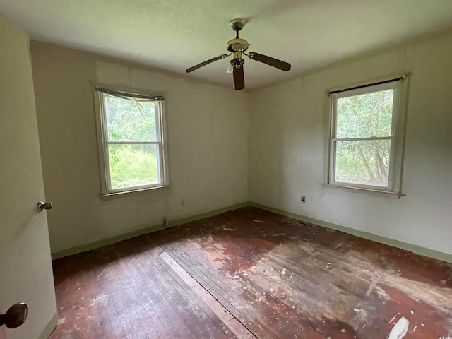 empty room featuring a wealth of natural light, ceiling fan, and dark wood-type flooring