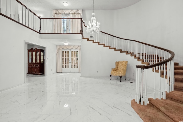 stairway with a notable chandelier, a towering ceiling, french doors, and plenty of natural light