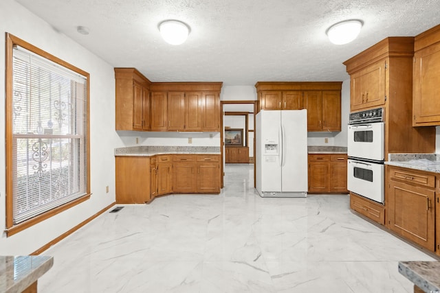 kitchen featuring a textured ceiling and white appliances