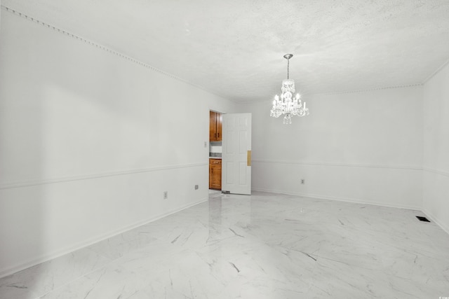 unfurnished room with a notable chandelier and a textured ceiling