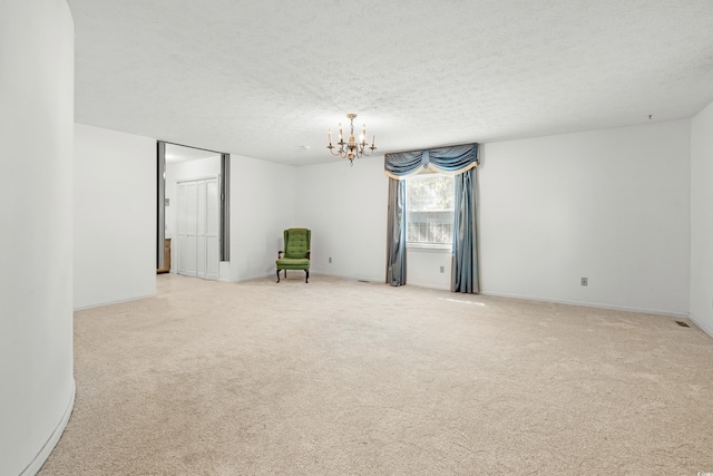 carpeted spare room featuring a textured ceiling and a notable chandelier