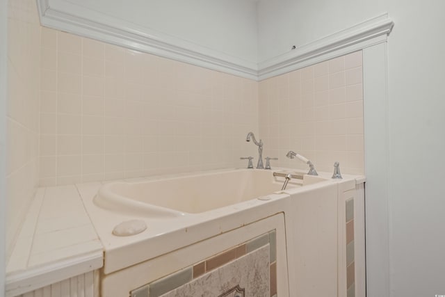 bathroom featuring ornamental molding and a tub