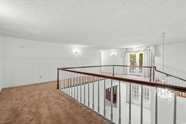 hallway featuring carpet floors, a notable chandelier, and a textured ceiling