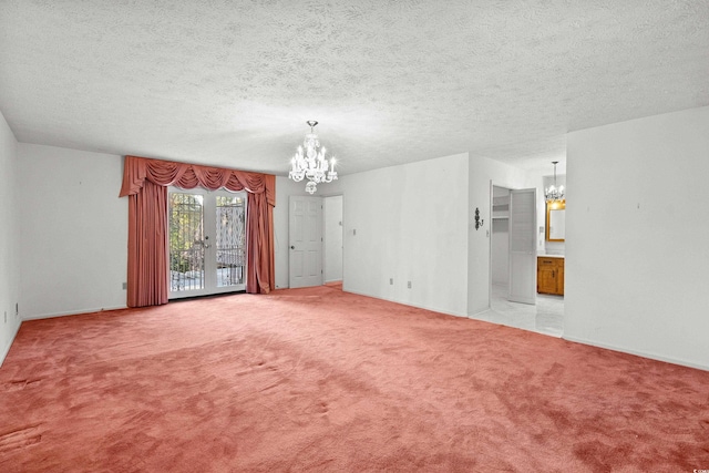 spare room featuring light carpet, a notable chandelier, and a textured ceiling