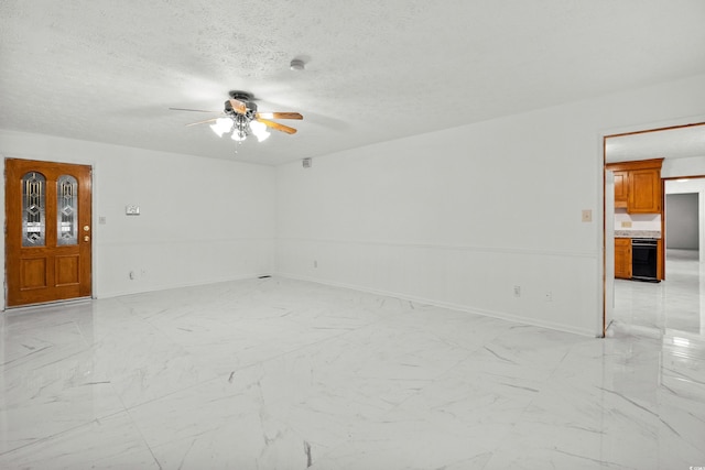 empty room with ceiling fan and a textured ceiling