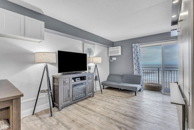 living room featuring a textured ceiling, light hardwood / wood-style flooring, and a wall mounted AC