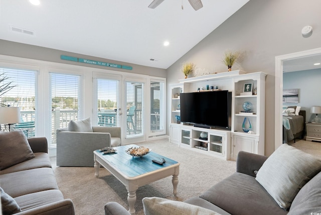 carpeted living room with ceiling fan and high vaulted ceiling