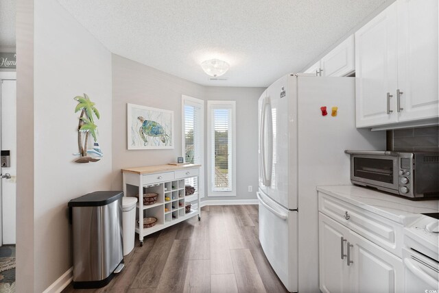 4755 Lightkeepers Way Unit 15-F, Little River, SC 29566 - kitchen featuring dark wood finished floors, white cabinetry, freestanding refrigerator, baseboards, and a textured ceiling