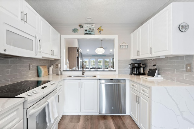 kitchen featuring white cabinetry, decorative light fixtures, sink, dark wood-type flooring, and white appliances