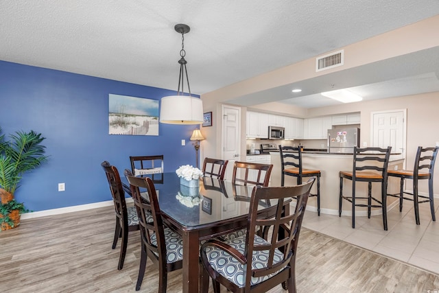 dining area with light hardwood / wood-style flooring and a textured ceiling