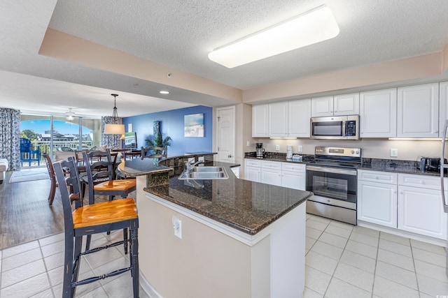 kitchen with decorative light fixtures, sink, stainless steel appliances, and white cabinets