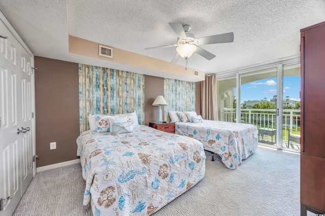 carpeted bedroom featuring ceiling fan, access to exterior, expansive windows, and a textured ceiling