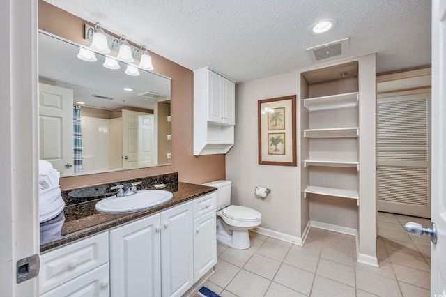 bathroom with a textured ceiling, tile patterned flooring, vanity, and toilet