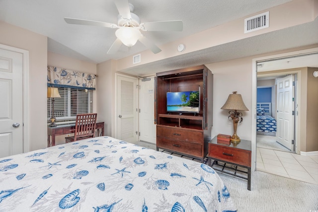 bedroom with ceiling fan, light colored carpet, and a textured ceiling