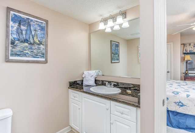 bathroom with ceiling fan, a textured ceiling, vanity, and toilet