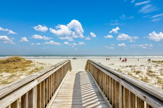 view of property's community featuring a water view and a beach view