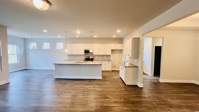 kitchen featuring a center island with sink, dark hardwood / wood-style floors, decorative light fixtures, white cabinetry, and stainless steel appliances