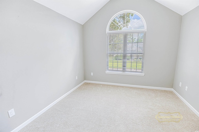 carpeted spare room with vaulted ceiling