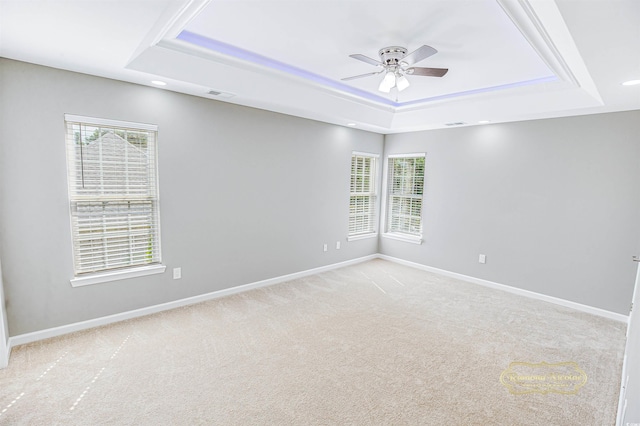 unfurnished room featuring ceiling fan, a raised ceiling, and light carpet