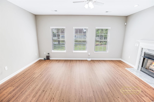 unfurnished living room featuring ceiling fan, a fireplace, and light hardwood / wood-style floors