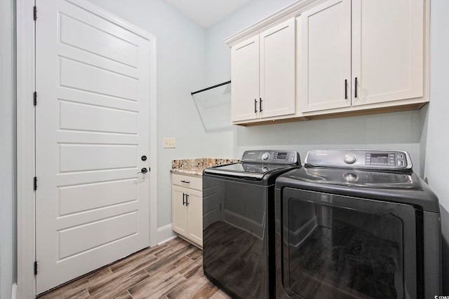 laundry room featuring washing machine and dryer, light hardwood / wood-style flooring, and cabinets