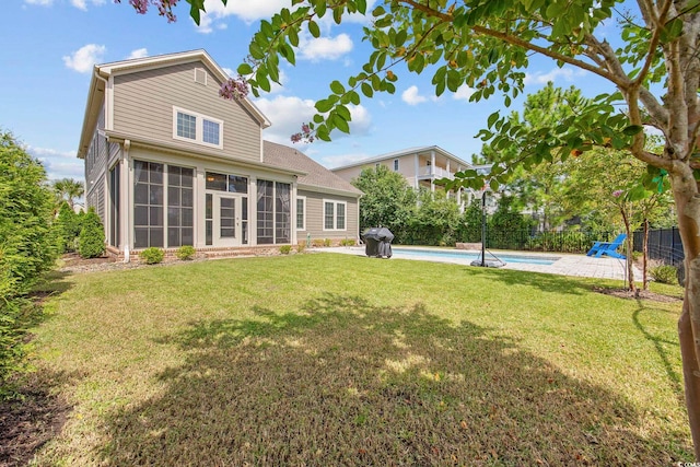 rear view of house with a sunroom, a fenced in pool, and a yard