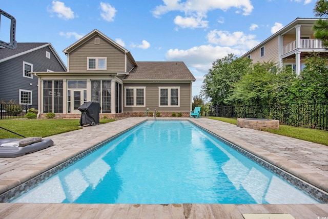 view of swimming pool featuring a sunroom, area for grilling, and a yard