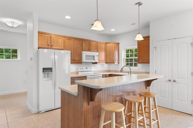 kitchen with light tile patterned flooring, a kitchen breakfast bar, hanging light fixtures, and white appliances