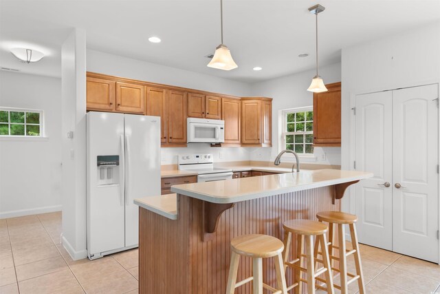 kitchen with light countertops, light tile patterned floors, a healthy amount of sunlight, and white appliances