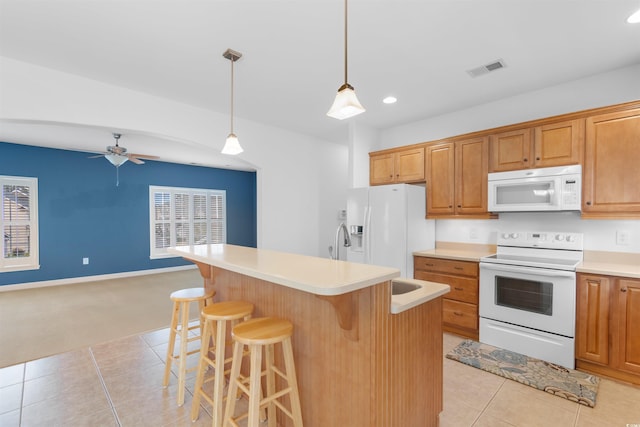 kitchen featuring light countertops, a breakfast bar area, white appliances, light tile patterned flooring, and ceiling fan