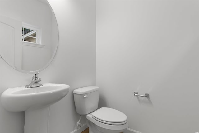 half bathroom featuring toilet, a sink, and baseboards